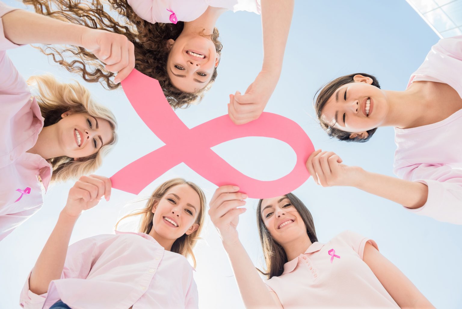 Women holding a pink ribbon for Breast Cancer Awareness Month